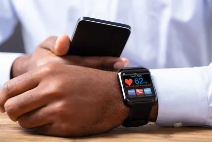 Person checking their heart rate on their smart watch while looking at their smart phone.